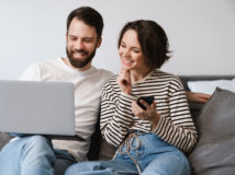 Happy young white couple sitting on a couch at home